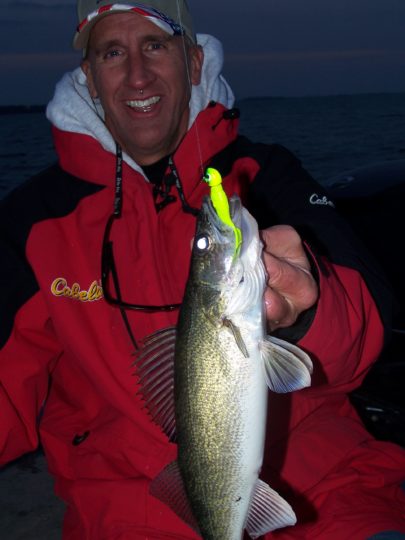 Fisherman holds up a walleye he caught while night fishing
