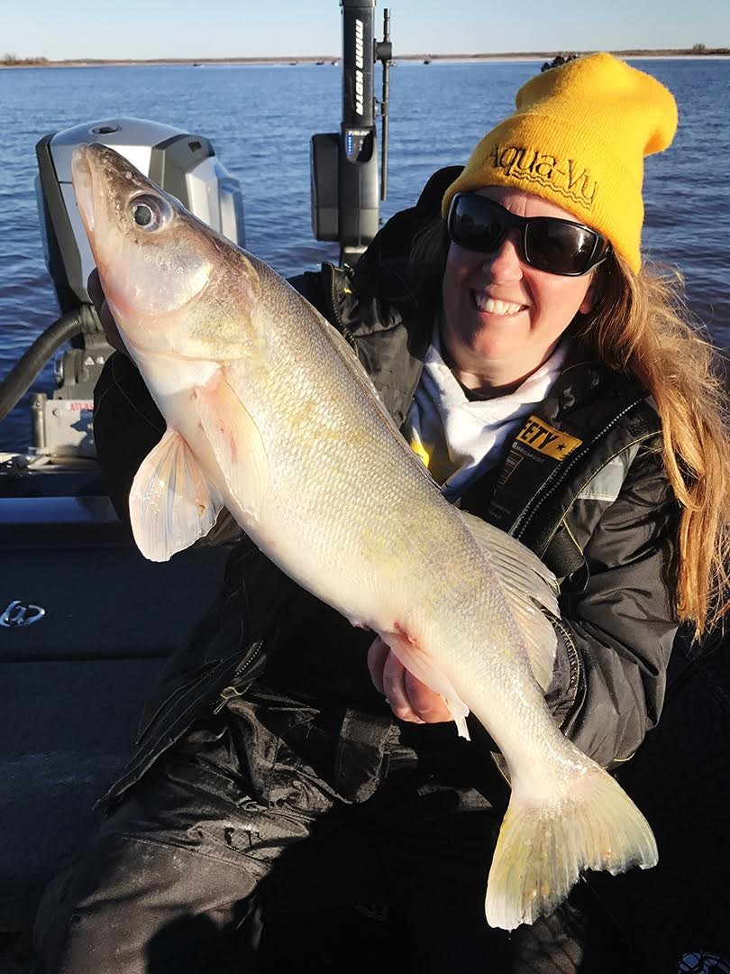 A female fisherman holding up an early season walleye.