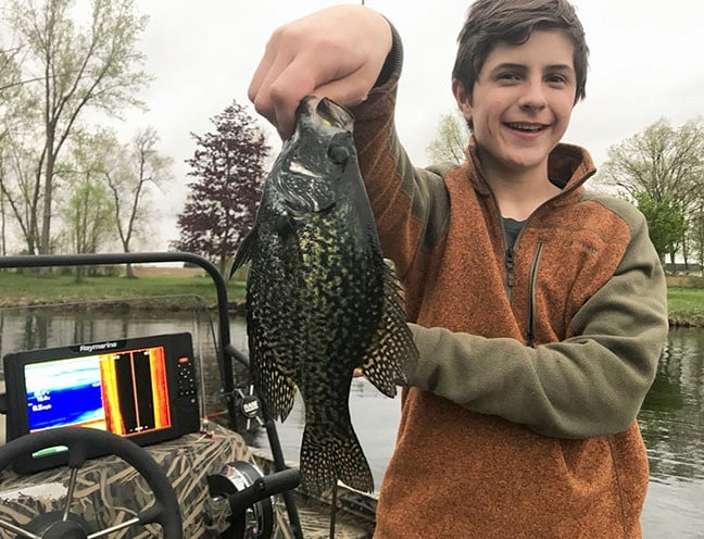 Youth angler holding up a black crappie that was caught on a Northland Fishing Tackle jig.