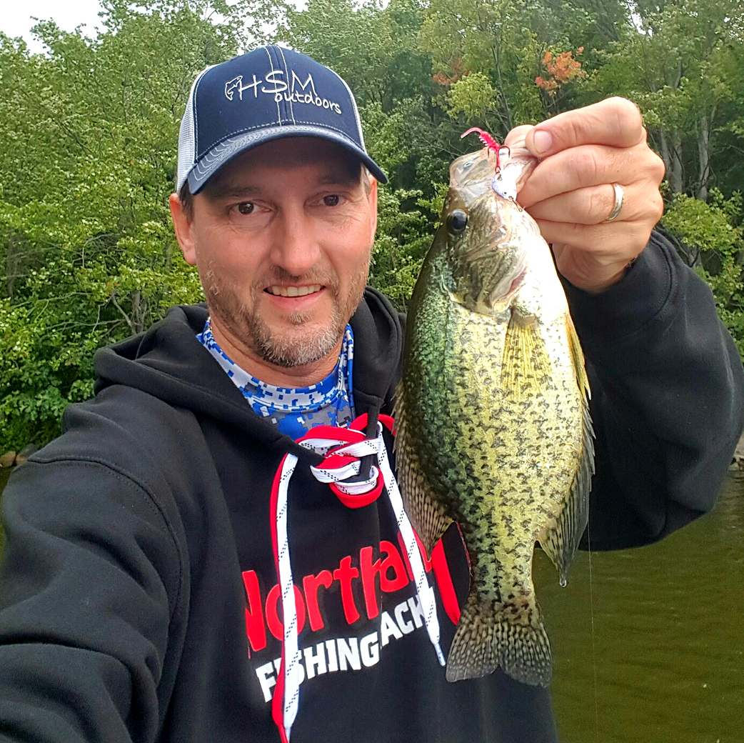 Fisherman holding up a crappie he caught fishing.