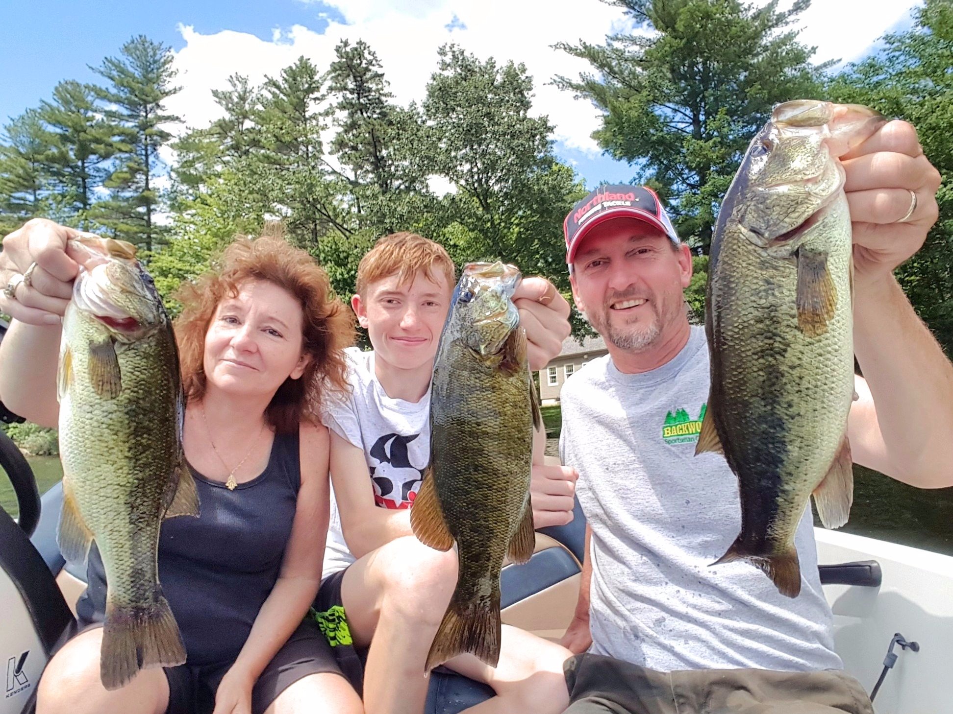 Three fisherman holding up largemouth and smallmouth bass they caught.