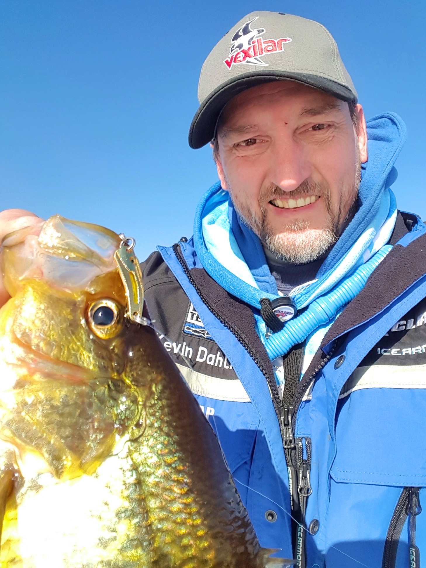 Fisherman holding up a crappie they caught ice fishing.