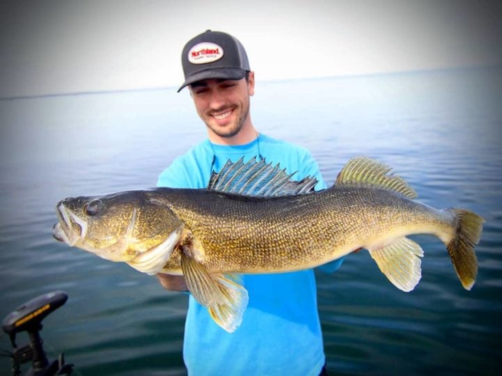 Fisherman holding up a big walleye he caught in shallow water