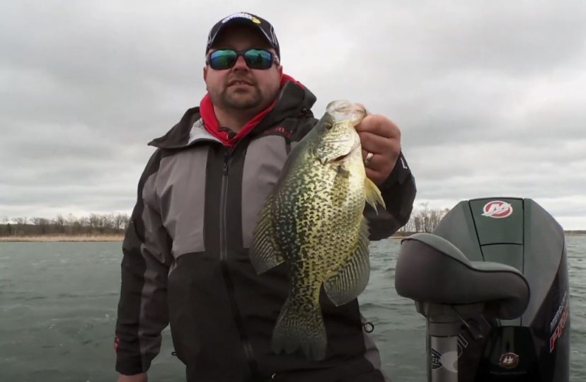 Fisherman holding up an early spring crappie he caught fishing.