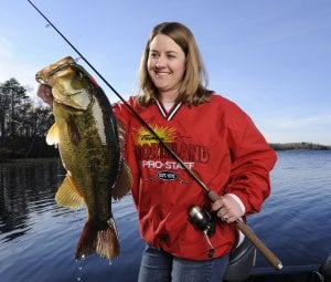 Female bass fisherman holding up a bass caught on a soft plastic