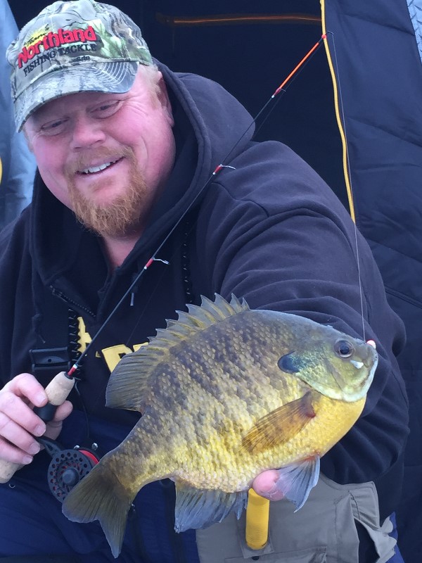 Fisherman with a bluegill he caught ice fishing.