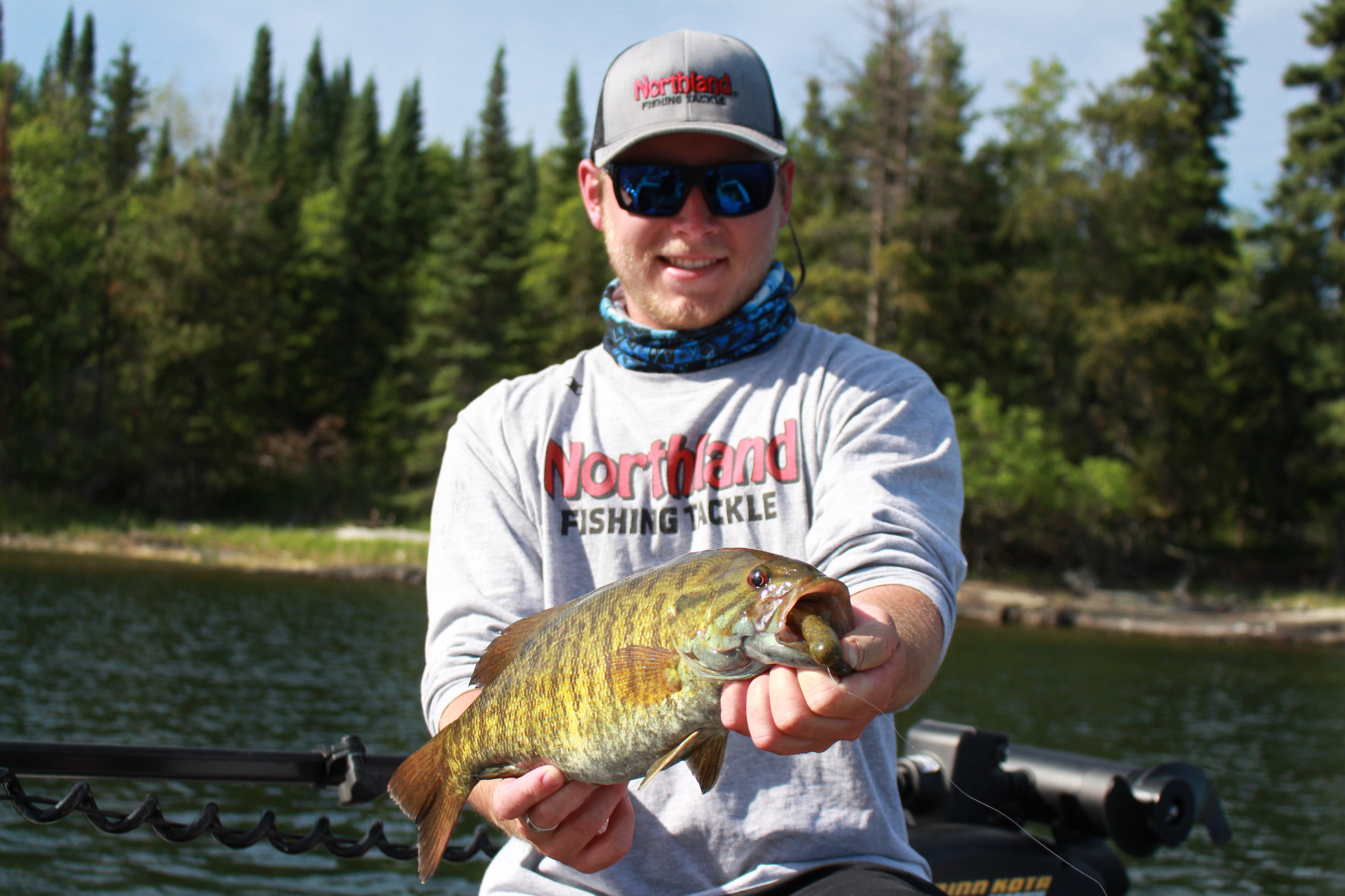 Fisherman on Lake of the Woods holding up a smallmouth bass he caught.