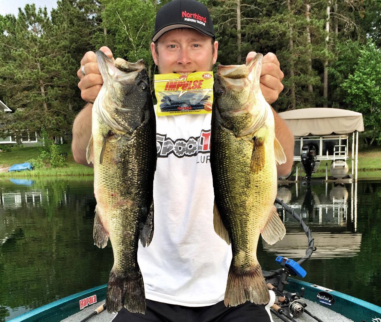 Fisherman holding up two big largemouth bass he caught on a lake