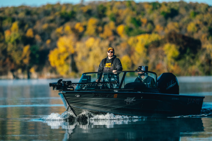 Fisherman in a boat in the fall looking for first ice spots