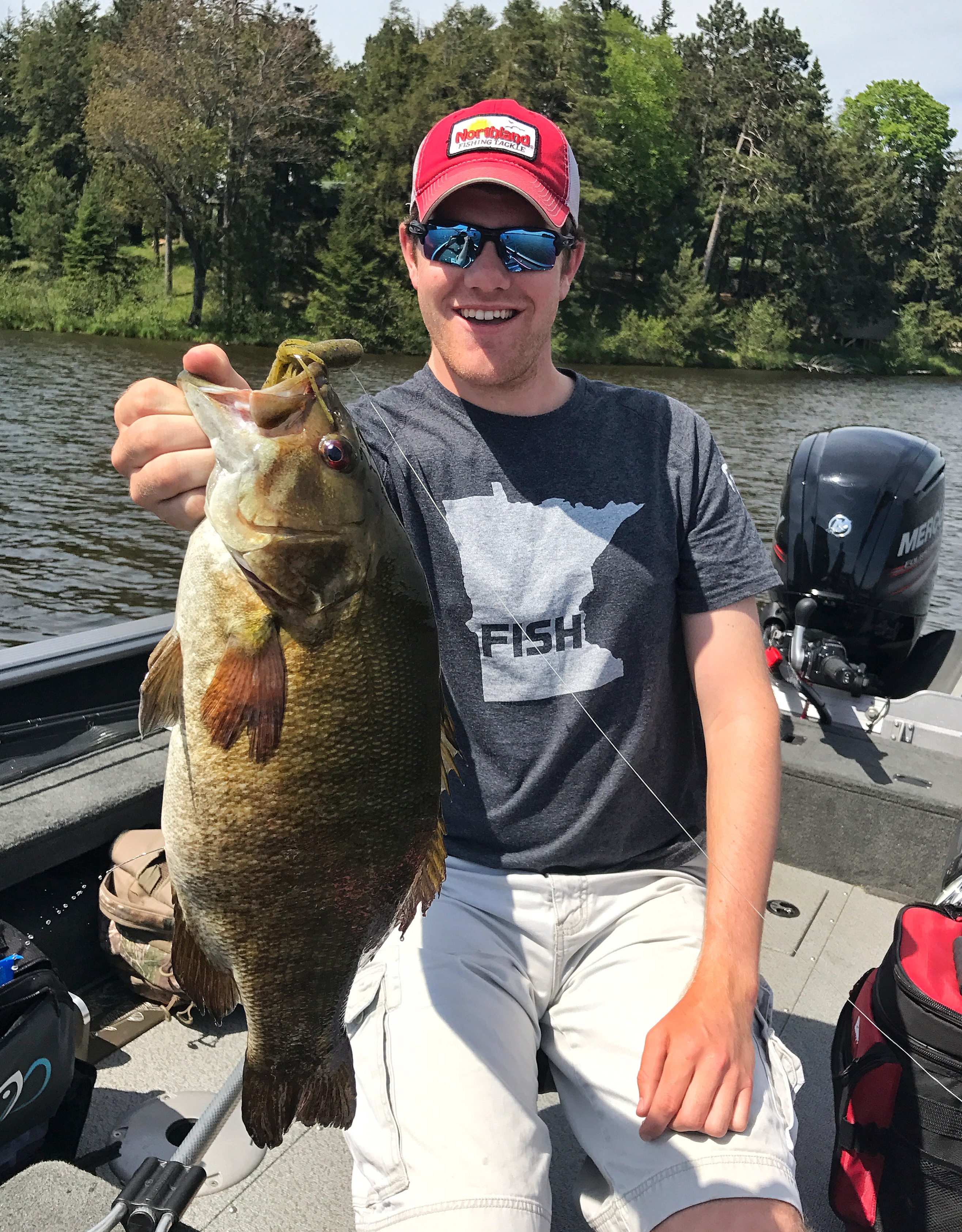 Fisherman holding a smallmouth bass up he caught on a soft plastic tube bait.