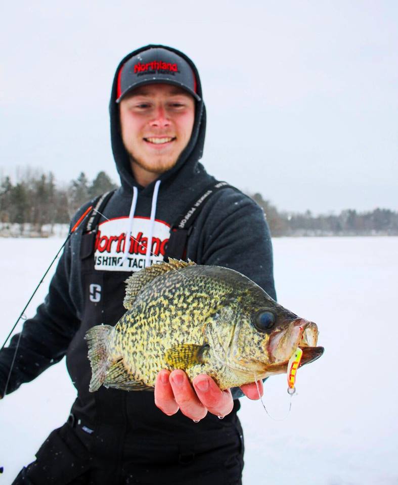 Fisherman with a crappie caught ice fishing with a spoon.