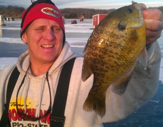 Mike Frisch ice fishing and holding up a bluegill he caught.