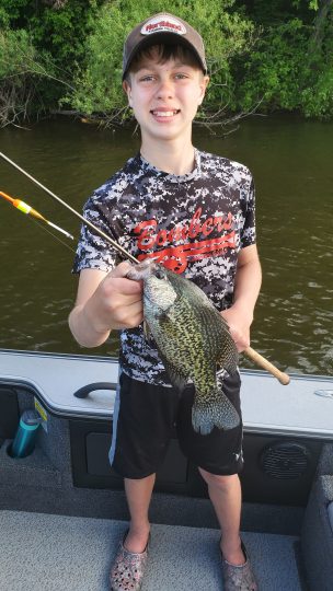 Young fisherman holding up a crappie he caught on a slip bobber set up.