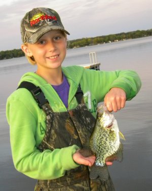 A young fisherman holding up a crappie they caught fishing.