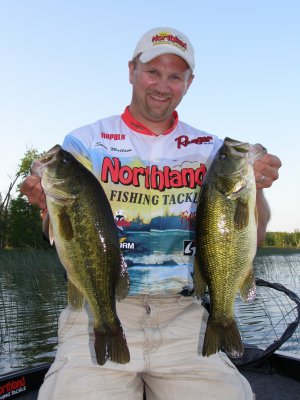 Steve Mattson holding up two largemouth bass caught on a jig