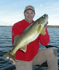 A fisherman holding up a big walleye caught on a jig.