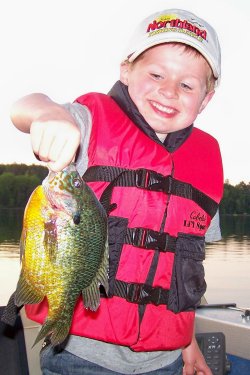 A young fisherman holding up a bluegill he caught.