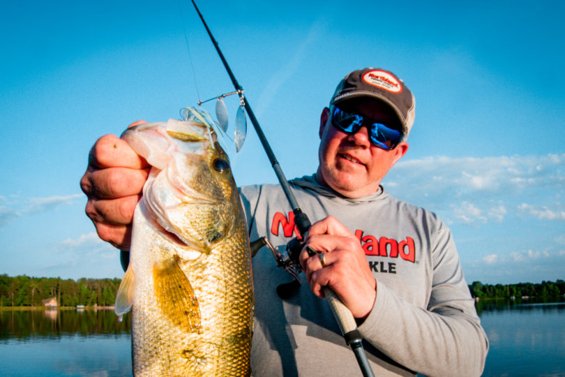 Fisherman holding up a largemouth bass caught on a Reed Runner Tandem spinnerbait