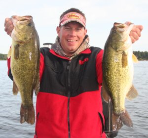 Fisherman holding up two big fall largemouth bass that he caught.