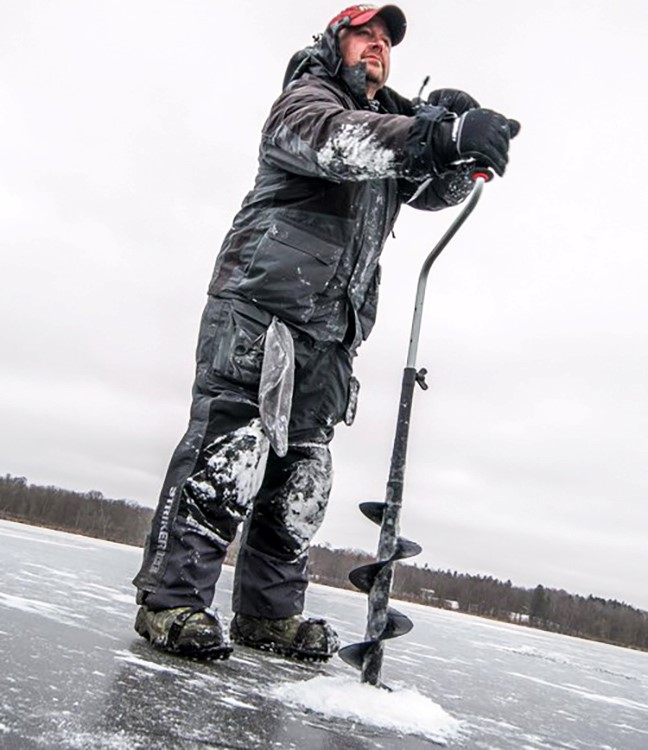 Ice fisherman drilling a hole in the ice with a hand auger