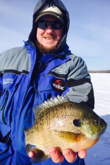 An ice fisherman with a blue gill they caught.