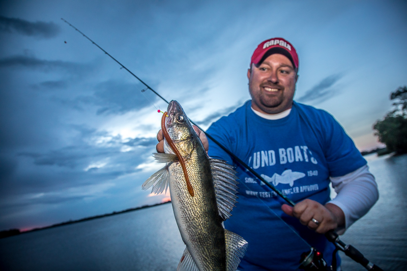 Fisherman holding up a walleye he caught fishing.