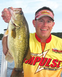 John Janousek holding up a largemouth bass caught on an Impulse soft plastic bait.