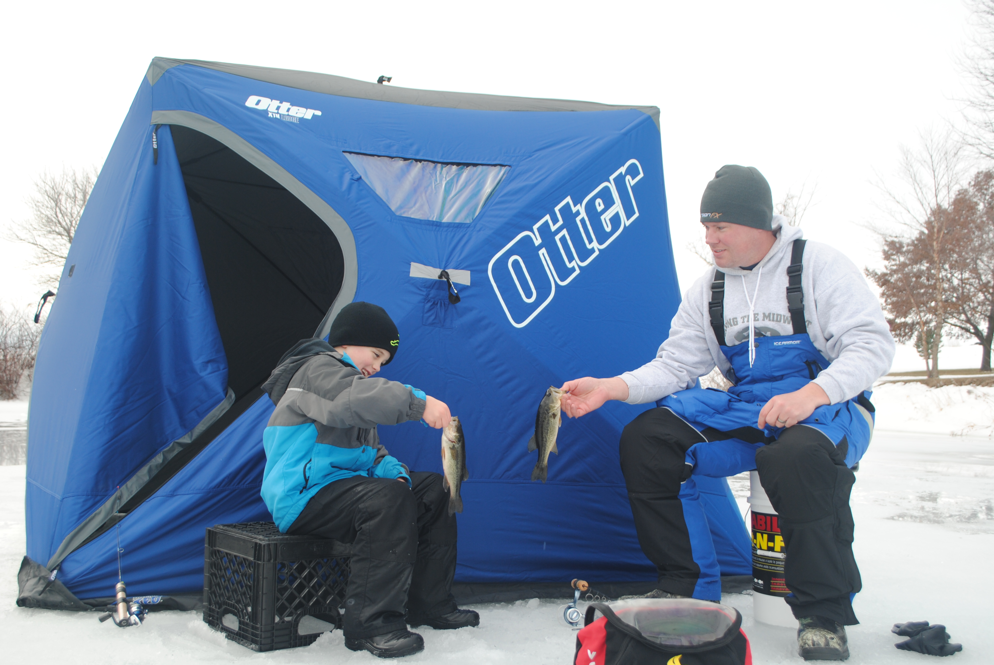 Adult fisherman and young angler ice fishing.