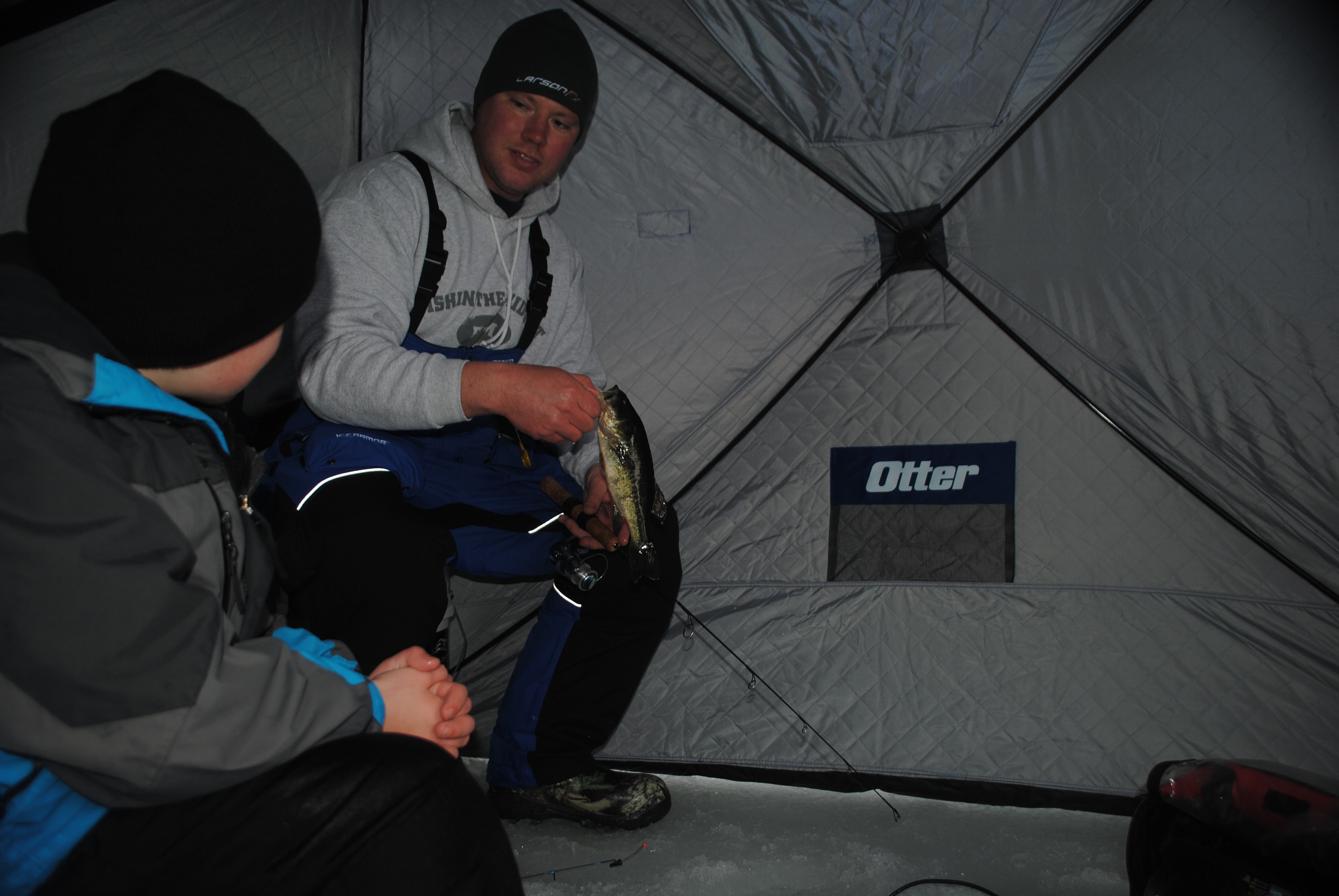 Fisherman ice fishing inside a pop up shelter.