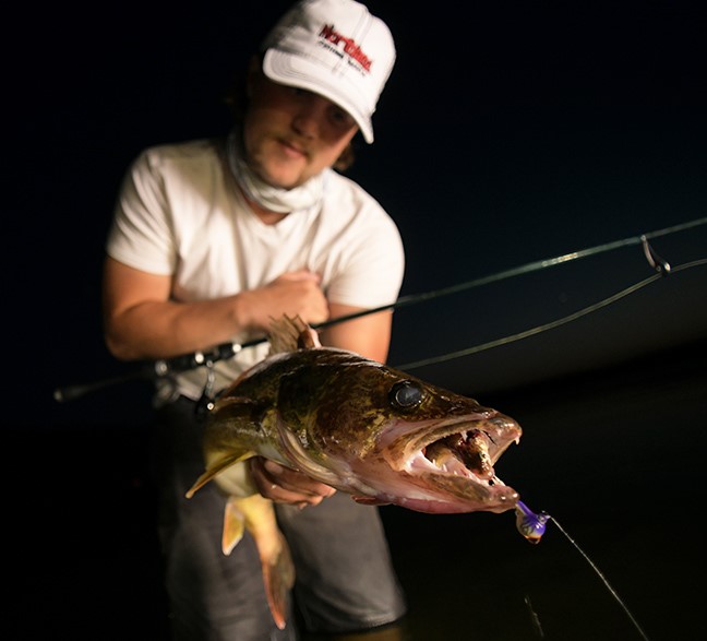 Angler holding up a walleye that he caught night fishing on a jig