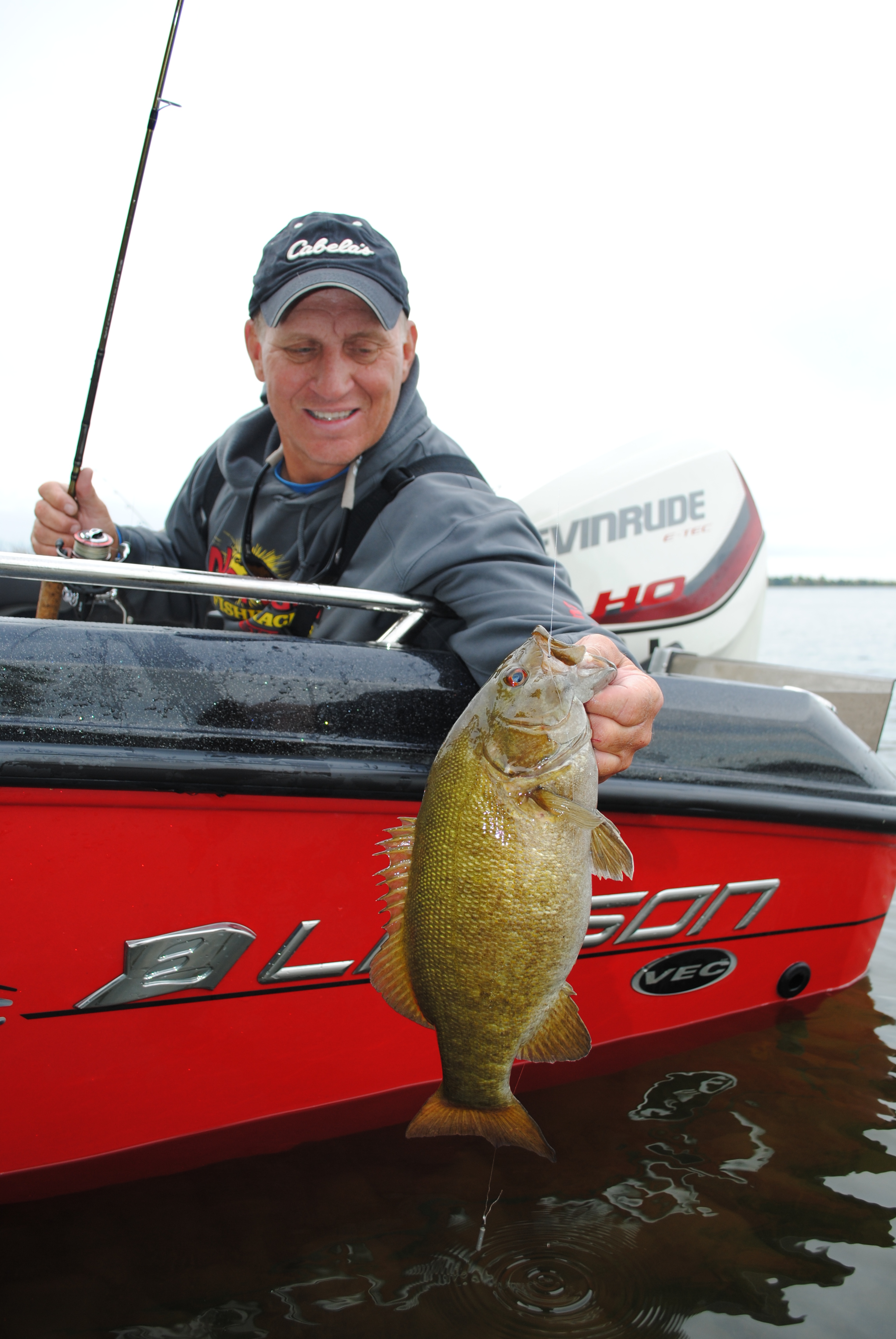 Mike Frisch going fishing and holding a smallmouth bass he caught